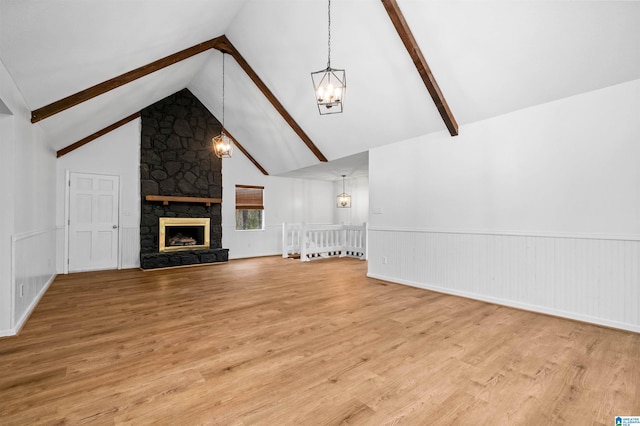 unfurnished living room with light hardwood / wood-style flooring, beam ceiling, high vaulted ceiling, a notable chandelier, and a fireplace