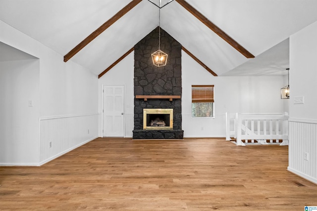 unfurnished living room with wood-type flooring, a fireplace, and vaulted ceiling with beams