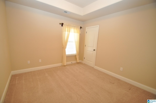 carpeted empty room with a raised ceiling