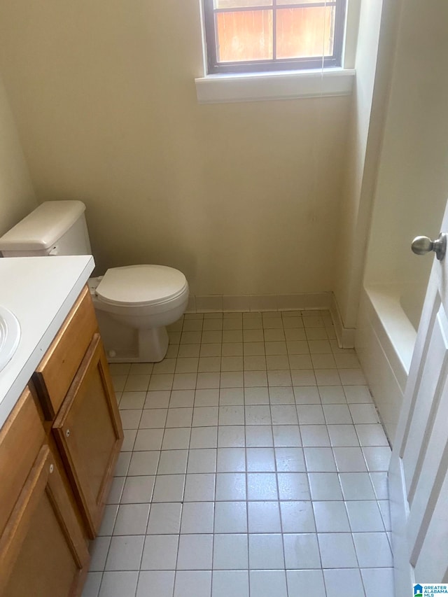 bathroom featuring vanity, a bath, tile patterned flooring, and toilet