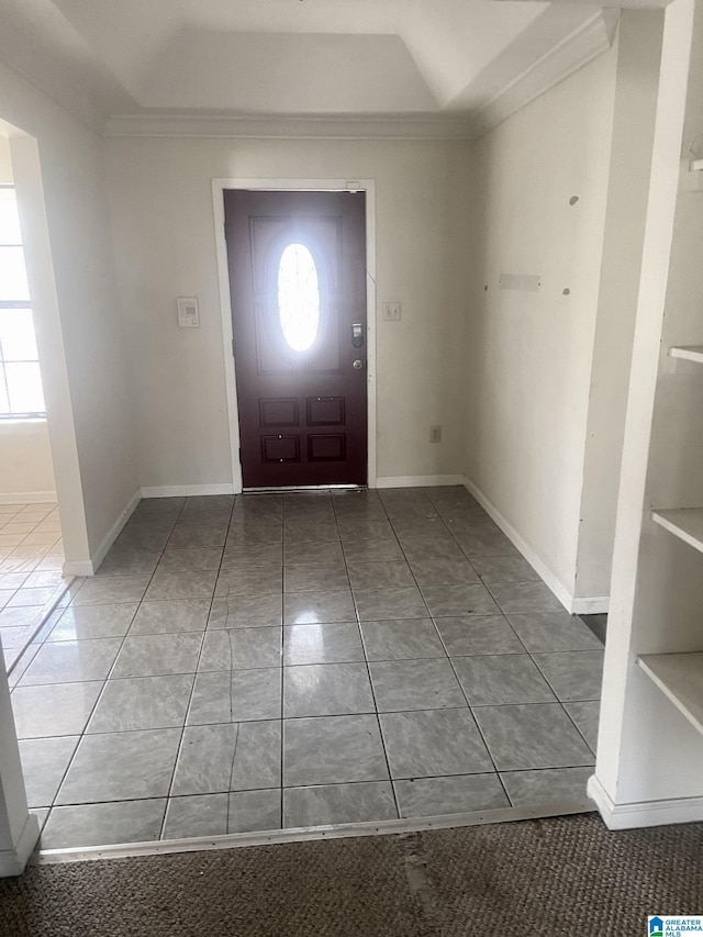 foyer entrance featuring tile patterned flooring, a raised ceiling, and crown molding