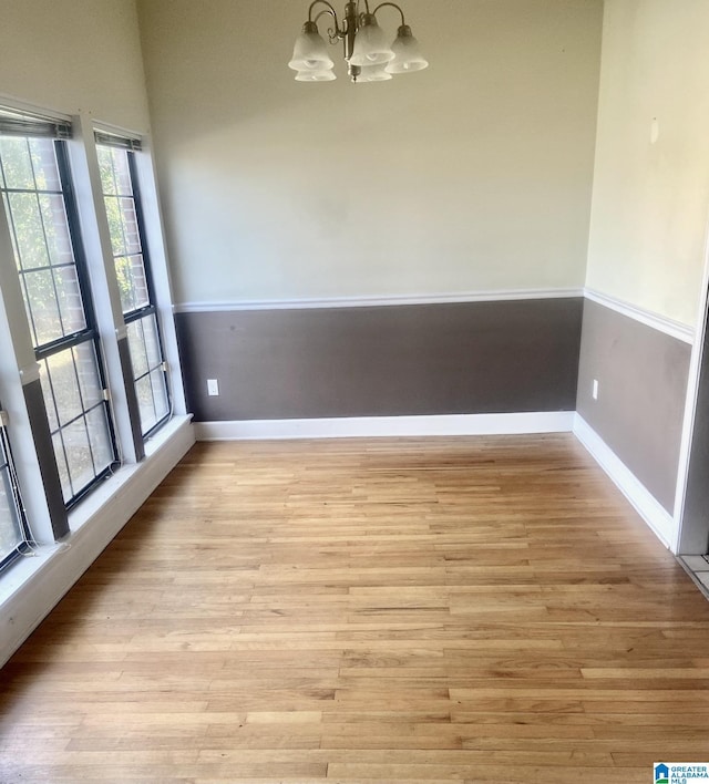 unfurnished dining area with light wood-type flooring and a chandelier