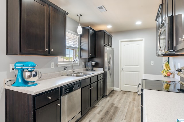 kitchen featuring dark brown cabinetry, sink, decorative light fixtures, appliances with stainless steel finishes, and light hardwood / wood-style floors