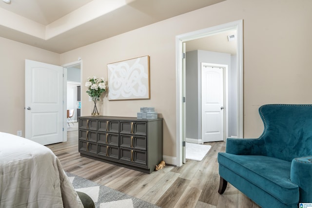 bedroom with a raised ceiling and light hardwood / wood-style flooring