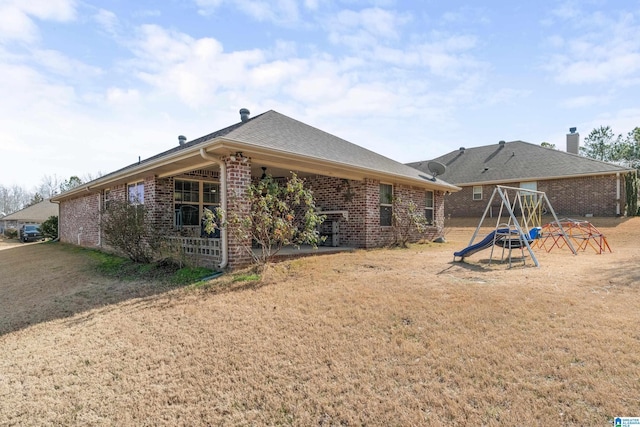 rear view of house featuring a playground and a lawn