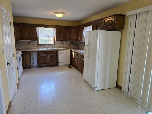 kitchen with sink, white appliances, light tile patterned floors, backsplash, and dark brown cabinets