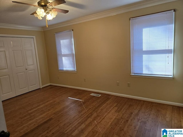 unfurnished bedroom with hardwood / wood-style floors, ornamental molding, a closet, and ceiling fan