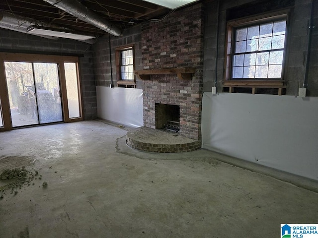 unfurnished living room with a brick fireplace and concrete floors