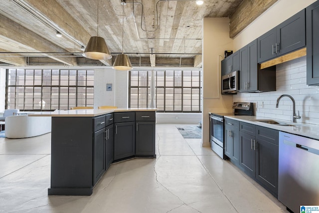 kitchen with appliances with stainless steel finishes, pendant lighting, sink, decorative backsplash, and a center island