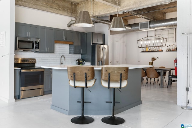 kitchen featuring stainless steel appliances, a breakfast bar area, gray cabinets, and pendant lighting