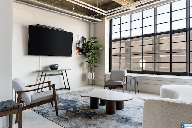 interior space featuring a towering ceiling, concrete flooring, and brick wall