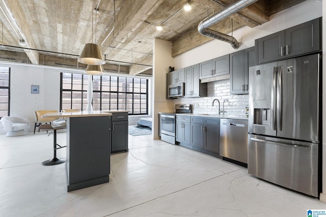 kitchen featuring sink, a breakfast bar area, appliances with stainless steel finishes, tasteful backsplash, and a kitchen island