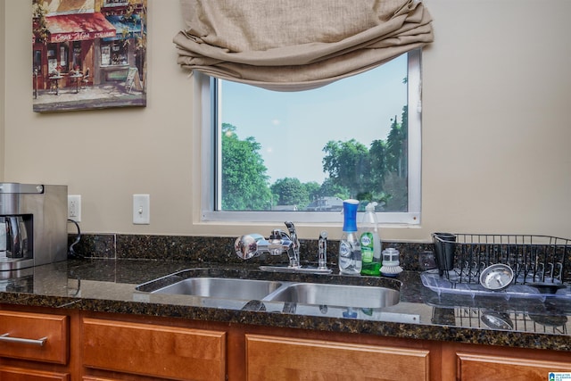 kitchen featuring a sink, dark stone counters, and brown cabinetry