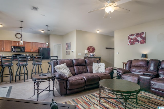 living room with light tile patterned floors, visible vents, and a ceiling fan