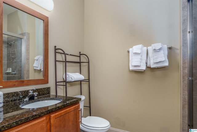 bathroom with baseboards, toilet, vanity, and a tile shower