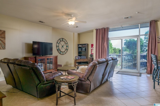 living area featuring ceiling fan, light tile patterned floors, visible vents, and expansive windows