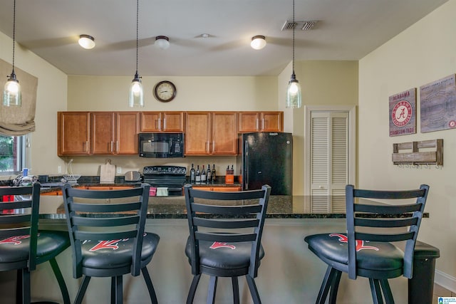 kitchen with pendant lighting, brown cabinets, black appliances, and a breakfast bar area