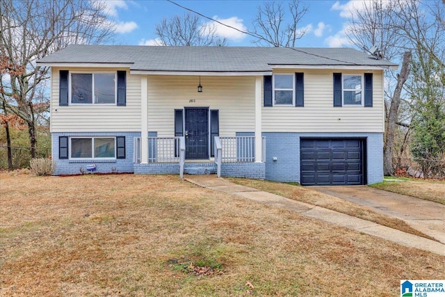 raised ranch with a garage, covered porch, and a front lawn