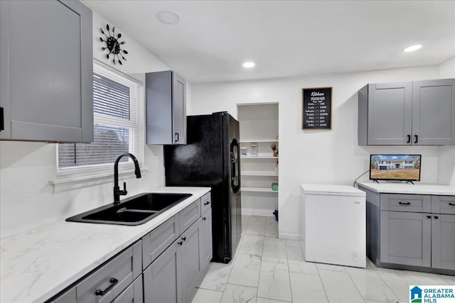 kitchen with gray cabinetry, sink, black fridge with ice dispenser, and refrigerator