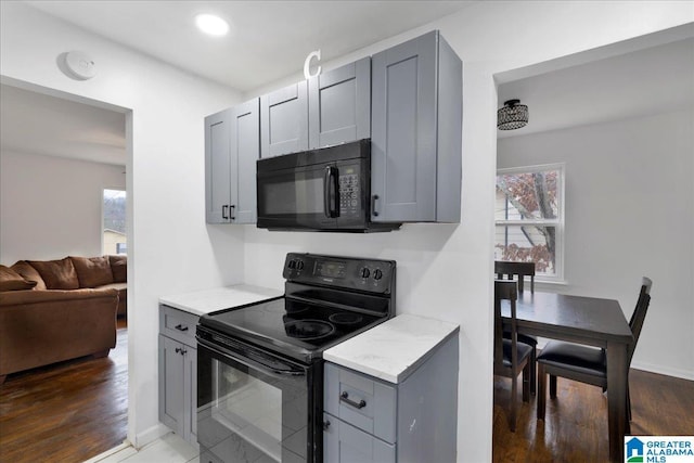 kitchen featuring gray cabinetry, dark hardwood / wood-style flooring, and black appliances