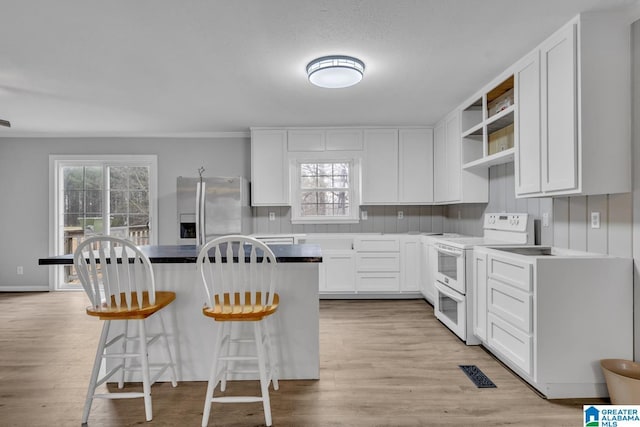 kitchen featuring crown molding, stainless steel fridge, a kitchen breakfast bar, white cabinets, and white electric stove