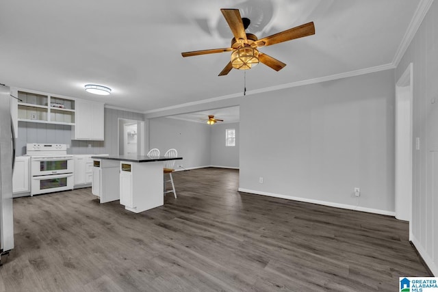 kitchen with a breakfast bar, a center island, double oven range, ornamental molding, and white cabinets