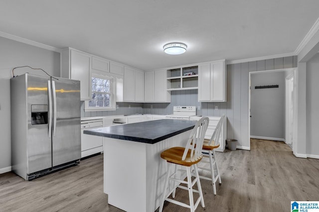 kitchen featuring white appliances, crown molding, white cabinetry, a kitchen breakfast bar, and a kitchen island