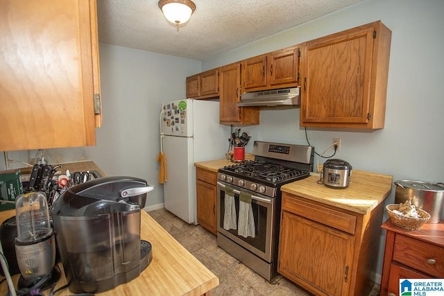 kitchen featuring stainless steel gas range, a textured ceiling, and white refrigerator