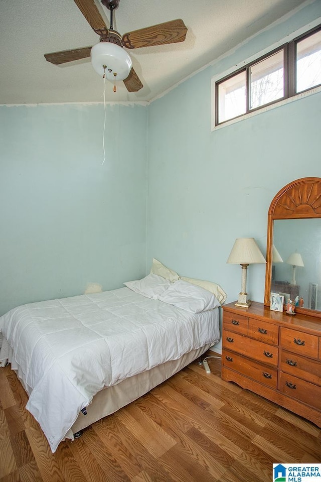 bedroom featuring hardwood / wood-style flooring, ornamental molding, and ceiling fan