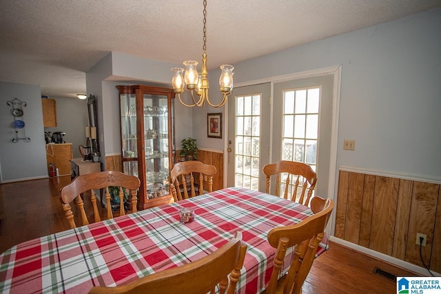 dining space featuring dark hardwood / wood-style flooring, wooden walls, and a textured ceiling