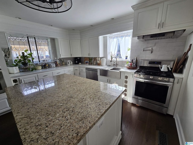 kitchen featuring stainless steel appliances, a center island, light stone counters, custom range hood, and white cabinets