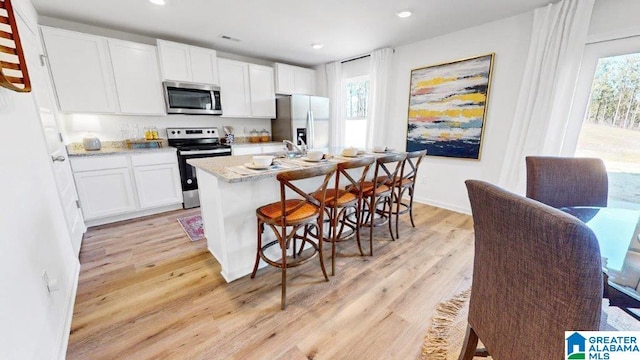 kitchen featuring white cabinetry, light stone counters, light hardwood / wood-style flooring, and appliances with stainless steel finishes