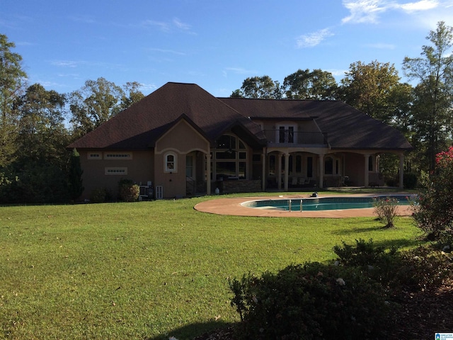 rear view of house with a balcony and a lawn