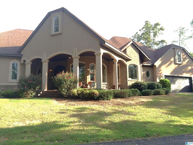 view of front of property featuring a porch, a garage, and a front yard