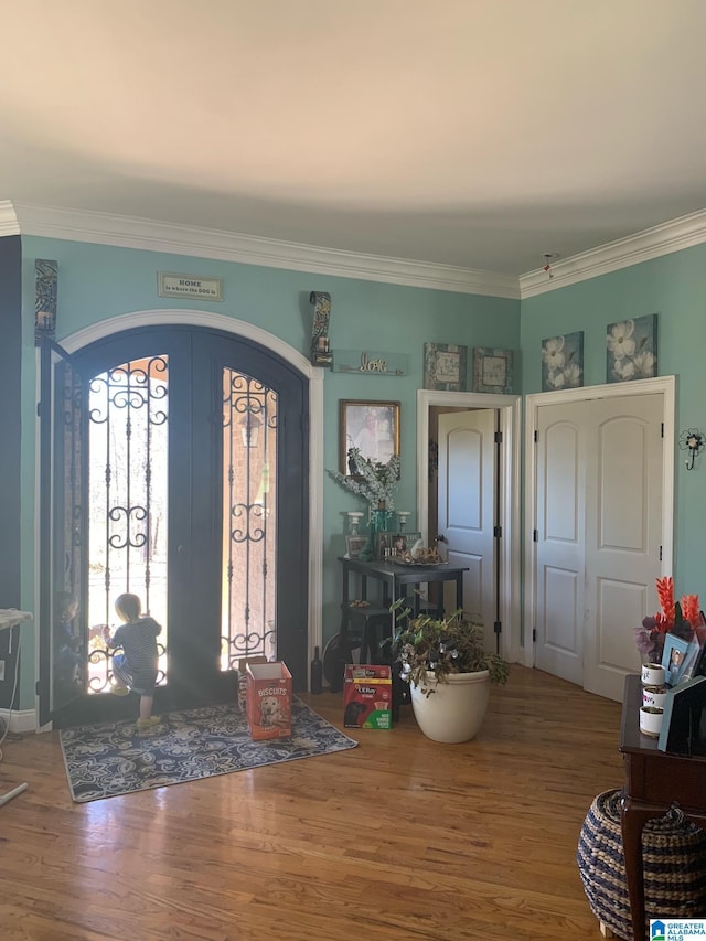 foyer entrance with crown molding, wood-type flooring, and french doors