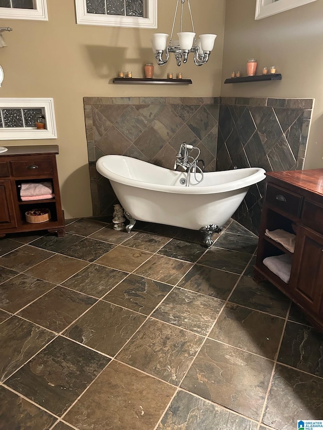 bathroom with vanity, a bath, a notable chandelier, and tile walls