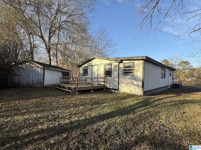 rear view of house featuring a lawn, an outbuilding, a garage, and a wooden deck