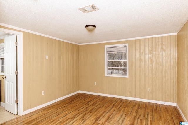 unfurnished room featuring a textured ceiling, crown molding, and wood-type flooring