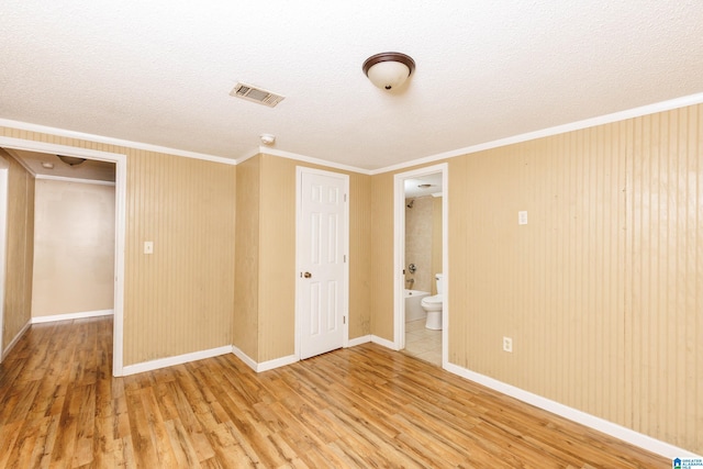 spare room with a textured ceiling, wood-type flooring, and ornamental molding