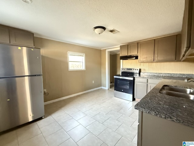 kitchen featuring dark stone countertops, sink, light tile patterned floors, a textured ceiling, and appliances with stainless steel finishes