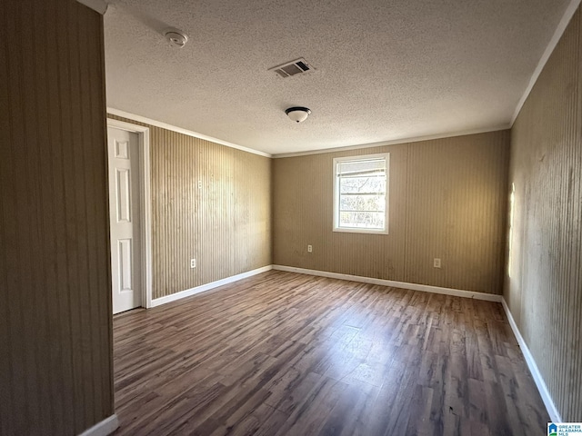 unfurnished room with a textured ceiling, ornamental molding, and dark wood-type flooring