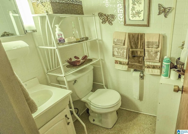 bathroom featuring vanity, toilet, and tile walls