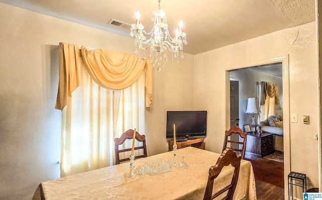 dining space with dark hardwood / wood-style flooring and an inviting chandelier