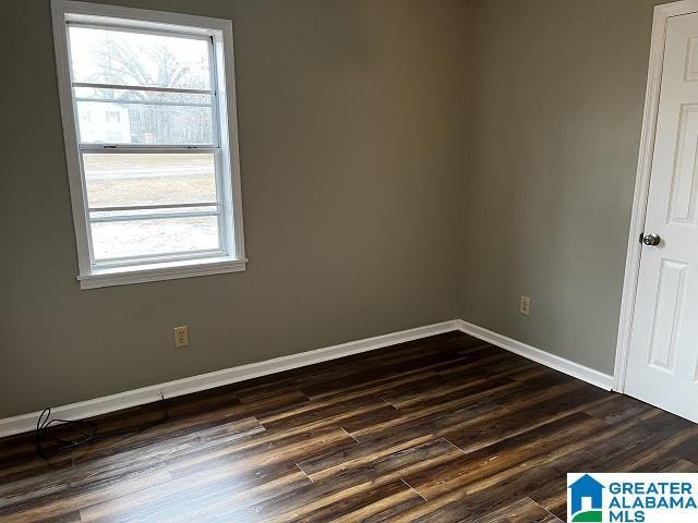 empty room featuring dark wood-type flooring and a healthy amount of sunlight