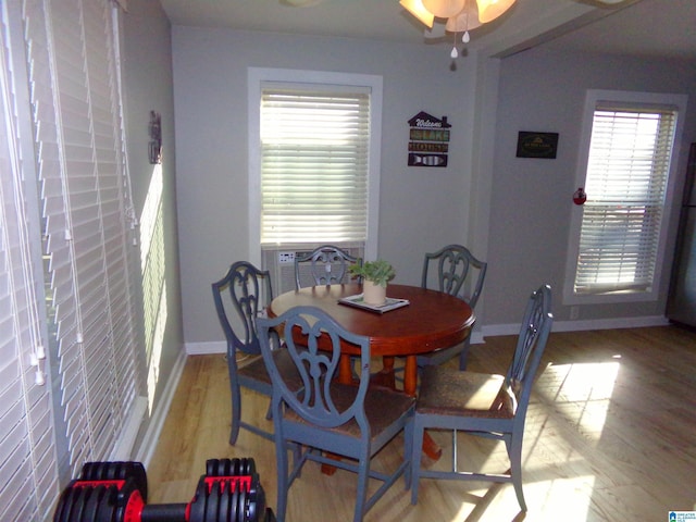 dining space featuring cooling unit, baseboards, and wood finished floors