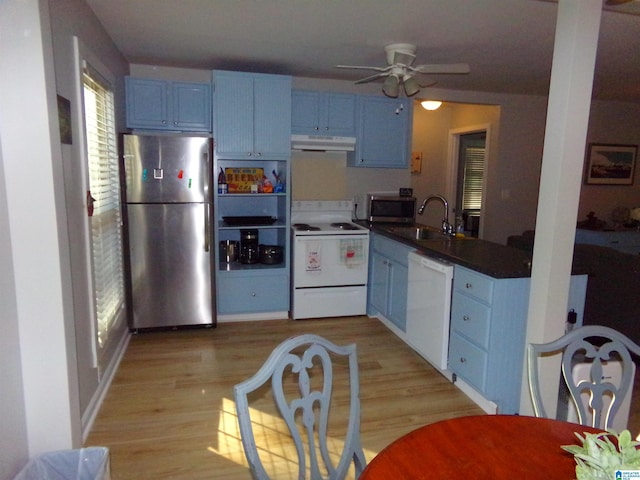 kitchen with light wood finished floors, appliances with stainless steel finishes, blue cabinets, under cabinet range hood, and a sink