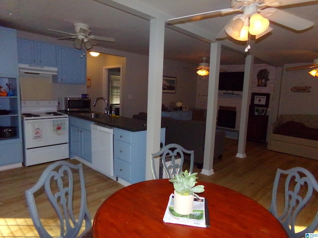 kitchen featuring a fireplace, light wood finished floors, a sink, white appliances, and under cabinet range hood