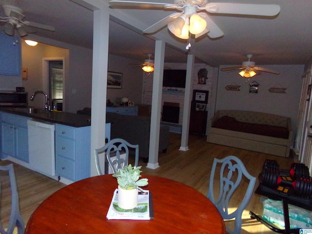 dining room with light wood-style floors, ceiling fan, and a fireplace