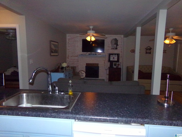 kitchen with a brick fireplace, open floor plan, a sink, ceiling fan, and dishwasher