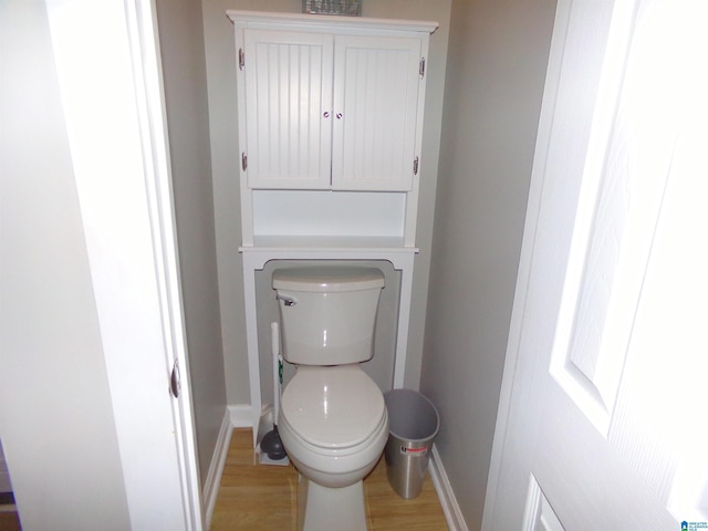 bathroom with wood finished floors, toilet, and baseboards